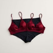 Flat lay of black bike shorts womens and seamless sports bras in burgundy, neatly folded on a neutral surface.