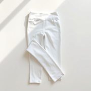Flat lay of white high waisted leggings with pockets neatly folded on a neutral surface, black high waisted leggings with pockets.