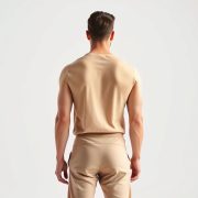 Back view of a model wearing a beige yoga outfit for guys, showcasing fit and cut in a studio with white background.